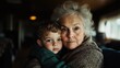 ©  Jovaduplex - An older woman with gray hair and a young boy hugging warmly in a dimly lit room, capturing the essence of familial affection and care within a cozy setting.