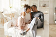© Anastasiya - Home comfort. Loving African American spouses relaxing, hugging while spending time together on weekend, couple cuddling in living room. High quality photo