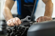 © zphoto83 - A mechanic works diligently on a vehicle engine with a wrench in a modern auto repair shop during daylight hours