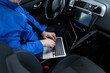 © zphoto83 - Technician working on a laptop in a car, troubleshooting electronic issues during an evening in an urban setting