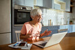 © Marko Geber - Senior woman working on laptop at home