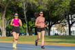 Two Latina women jogging outdoors in athletic wear on a sunny day