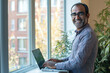 © Danny - Smiling Professional Man Typing on Laptop by Window in Modern Workspace – Remote Work and Business Success