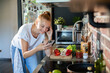 © Geber86 - Young woman filming cooking tutorial in kitchen with fresh vegetables and eggs