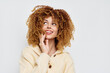 © SHOTPRIME STUDIO - Happy young woman with curly hair and bright smile, wearing a cozy knitted sweater Light background emphasizing her joyful expression
