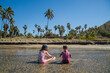 © Cavan Images - A boy and girl play in shallow water on beach