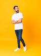 © luismolinero - Full-length shot of man with beard over isolated yellow background with arms crossed and happy