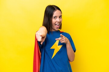 Young caucasian woman isolated on yellow background in superhero costume and fighting