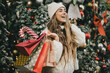 © polinaloves - Young beautiful womam enjoying Christmas shopping on a decorated street.