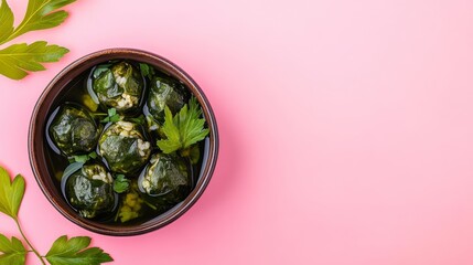 Top view of a bowl of stuffed grape leaves on a pink background with parsley sprigs.