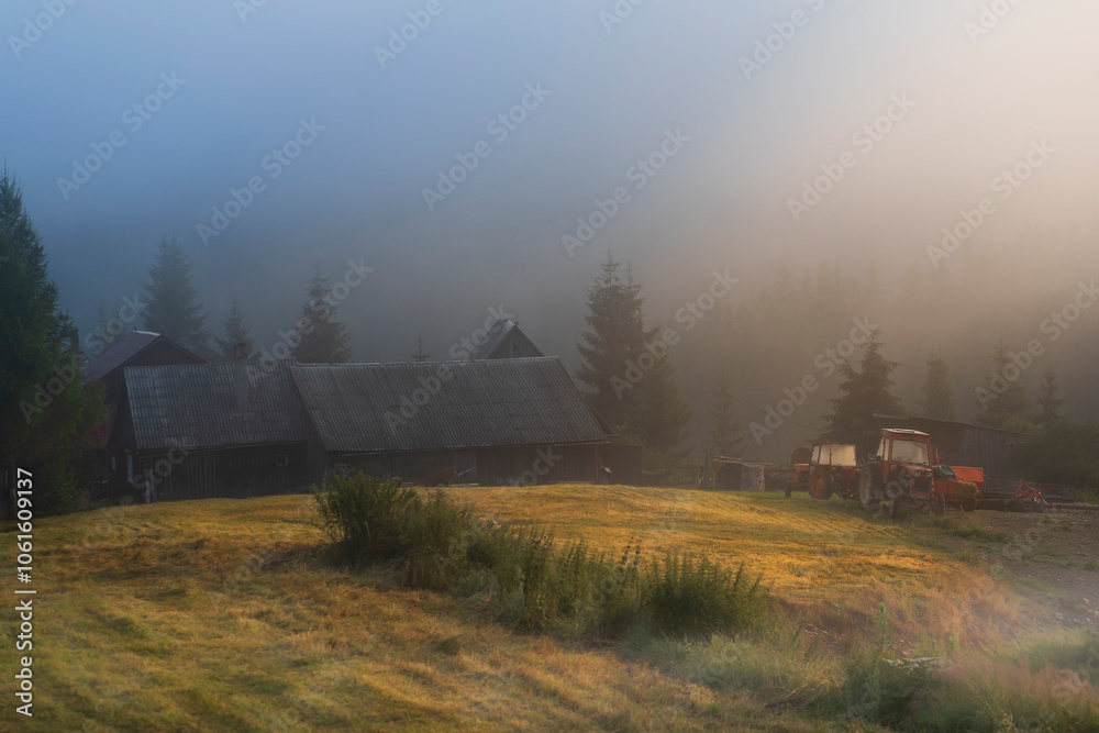 Old barn and farm equipment on a hill in the warm sunrise light on a ...