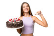 © luismolinero - Teenager caucasian girl holding birthday cake over isolated background proud and self-satisfied