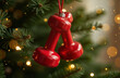 © Fotosova - A Christmas glass decoration in the shape of red dumbbells hangs on the Christmas tree, on a festive background, symbolizing sports and a healthy lifestyle during the holidays