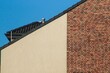 © Ulrich - Modern house facade combining plastered and brick walls with visible roof tiles and chimney against blue sky