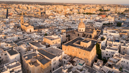 Aerial view ancient mediterranean town, houses church bell tower at sunrise, Monopoli, Puglia, Italy