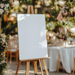 © Prasanth - A blank white welcome sign mockup, size is 24 by 36 inches in portrait orientation, on an easel during a wedding party.