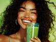 © Manutsanun - Smiling woman enjoying a refreshing green smoothie, captured against a vibrant background, exuding joy and health.