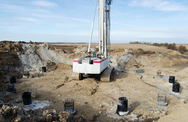 Wall Mural - Building activity on contruction site.Drilling machine.Wind turbine construction.
Excavator and other construction equipment.