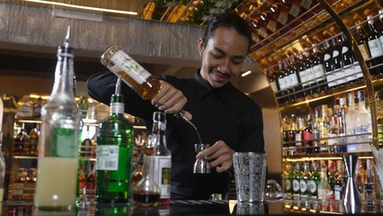 Asian bartender pouring mixed cocktail juice liqueur all ingredient into sliver shaker alcohol drink, making special advertisement creative tasty, focused refreshing showcase at bar luxury. Vinosity.