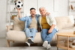 © Pixel-Shot - Mature man with his son watching football game at home