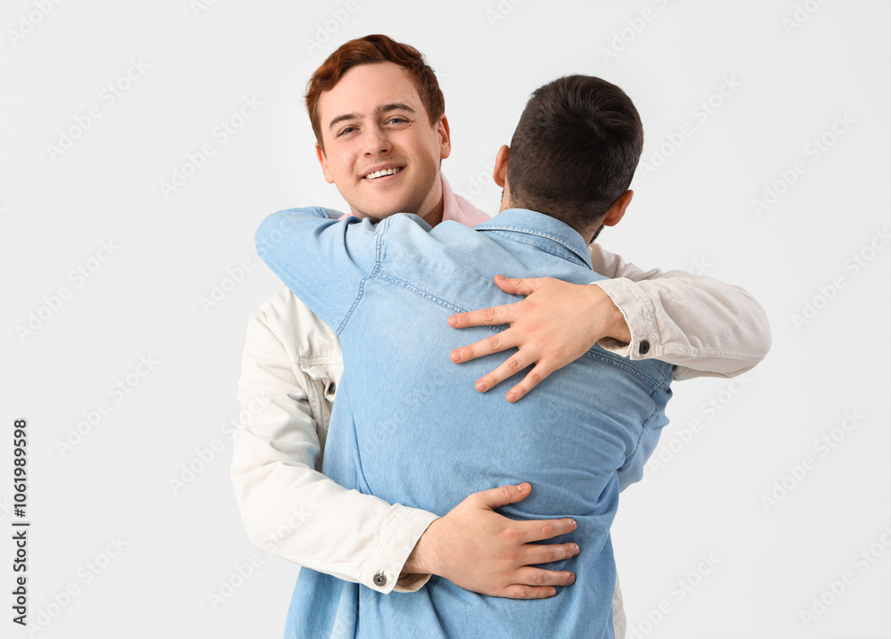 Male friends hugging on white background