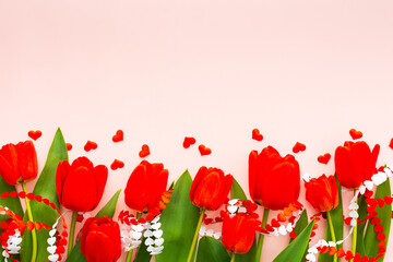 Fresh red tulips and hearts on pink background, concept of spring and holidays or Valentine's Day, top view, copy space