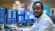 © PeopleWorker - Focus black man in a lab coat at a desk with multiple monitors