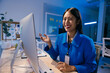 © Parichat - Asian businesswoman wearing a blue jacket is making a video conference on a desktop computer in a modern office at night, gesturing and smiling