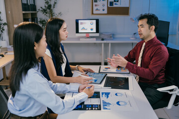 Fototapete - Business team discussing and analyzing financial charts and reports using digital tablet and printed documents during a productive office meeting