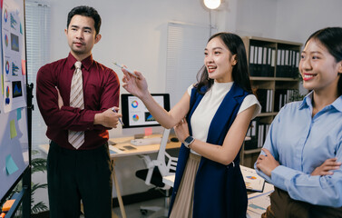 Poster - Businesswoman uses a pen to point at a whiteboard while presenting a business strategy to her colleagues in a modern office