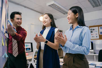 Fototapete - Group of young asian businesspeople clapping hands after a successful presentation, celebrating good teamwork and cooperation in office meeting
