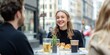 © kiimoshi - Young woman smiling with friends at a cafe table in a city street.