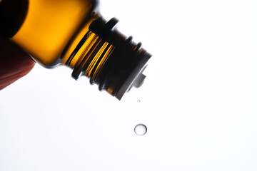 A drop of antihistamine or essential oil drips from a bottle. Close-up.