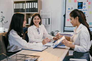 Aufkleber - Three asian businesswomen are analyzing financial reports and charts in a well-lit office, demonstrating teamwork and expertise in business management