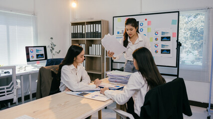 Aufkleber - Three asian businesswomen are working together in a modern office, analyzing financial reports, charts, and graphs while discussing company performance and strategies