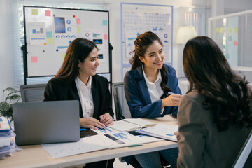 Fototapete - Three asian businesswomen are discussing strategy during an office meeting, analyzing charts and reports to improve performance and achieve goals