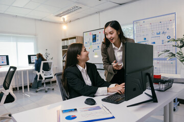 Poster - Two businesswomen are working together on a computer, discussing data and collaborating on a project in a modern office environment, showcasing teamwork and productivity