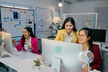 Poster - Asian businesswomen are working together, using desktop computer, analyzing financial charts, and collaborating on a project in a modern office
