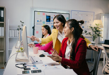 Aufkleber - Three asian businesswomen are smiling and collaborating on a computer project, pointing at the screen and discussing ideas in a modern office environment, showcasing teamwork and expertise