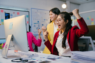 Poster - Three excited businesswomen are celebrating success in the office, raising their arms in front of a computer, showing enthusiasm and teamwork in achieving a business goal