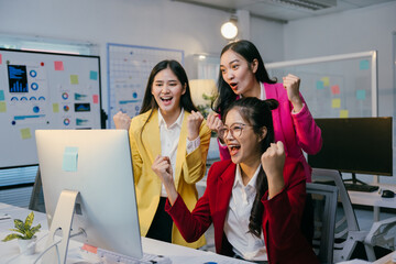 Aufkleber - Three excited businesswomen are celebrating success, raising their arms in front of a computer screen in a modern office environment, expressing joy and teamwork