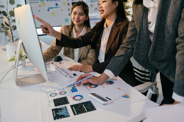 Fototapete - Asian businesswomen collaborate on a project, analyzing charts and documents, discussing findings in a modern office