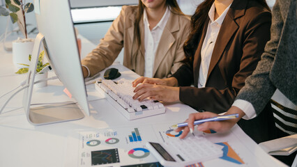 Aufkleber - Businesswomen are typing on a computer keyboard and analyzing financial charts and graphs, collaborating on a project in a modern office