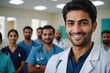 © ThomasLENNE - Close portrait of a smiling young Pakistani man doctor looking at the camera, Pakistani hospital blurred background