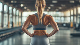 Młoda kobieta w obcisłych szarych legginsach fitness, z widokiem od tyłu, emanuje pewnością siebie i energią. 
