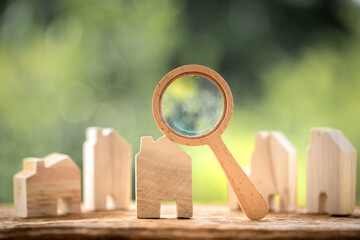 Many home model and magnifying glass put on the old wood on bokeh background in the public park, Loan for real estate and searching for choose the buy a new house to family in the future concept.