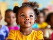 © Sergey - A young child with an attentive expression sits in a colorful classroom. The focus is on the child's bright clothing and curious eyes.