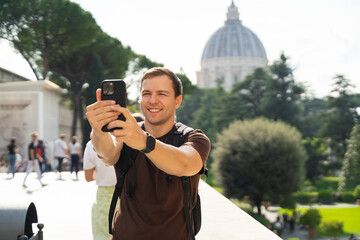 outdoor portrait of young man taking a selfie photo with his smart phone
