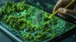 © BloomArt - Hand drawing a 3D city model on a digital tablet with a pencil, surrounded by green trees.