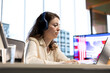 © DC Studio - Young woman leader listening to a podcast while she solves daily business tasks in high end office, corporate success story. Female CEO working with music in her headphones, determination.